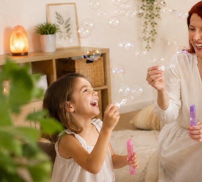 Une petite fille et Alexandra Richard soufflent des bulles de savon pendant une séance de sophrologie enfant